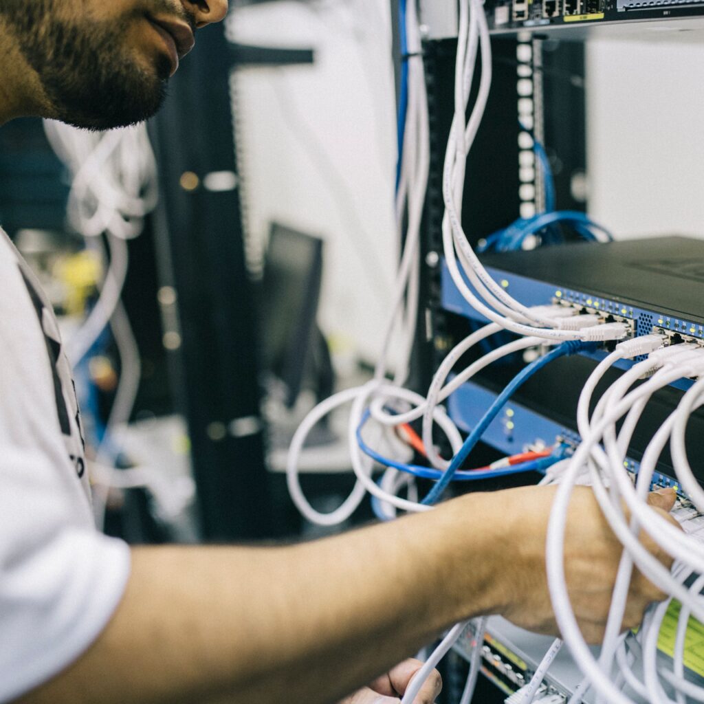 An IT professional configuring network cables in a server rack, focusing on Ethernet connections.